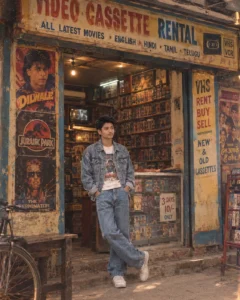 man standing near shelves of old vhs movie tapes